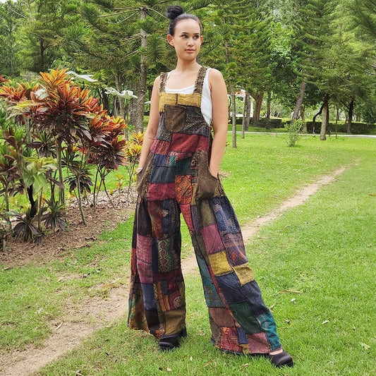 Woman wearing black patchwork jumpsuit overall in a park, front view.