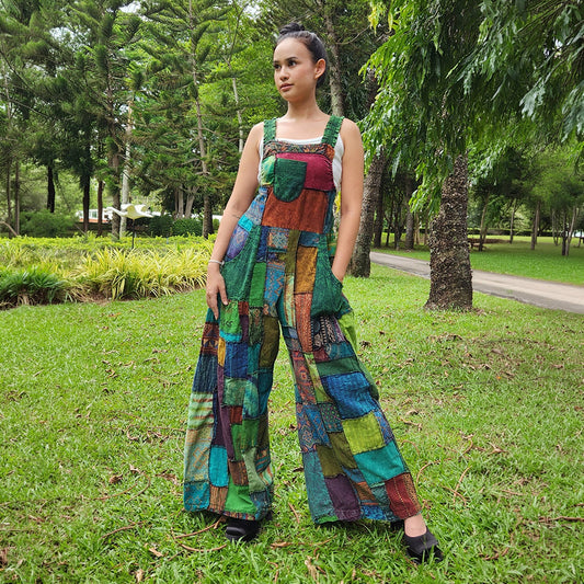 Woman wearing green patchwork jumpsuit overall in a park, front view.