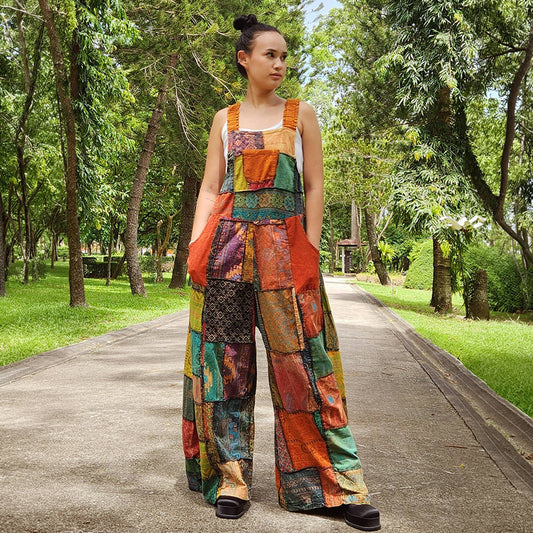 Woman wearing orange patchwork jumpsuit overall in a park, front view.
