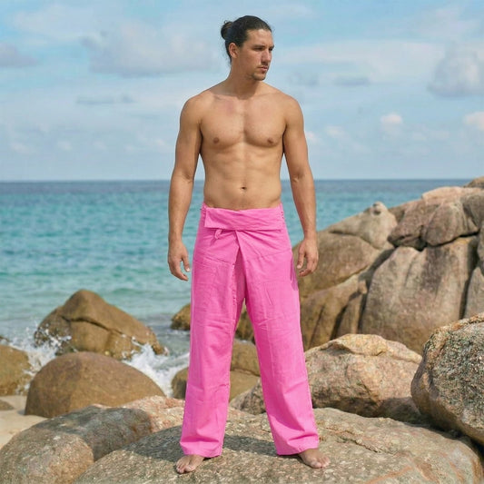 Male model posing on a beach wearing versatile Pink Paradise men's Thai fisherman pants in a wrap around style.