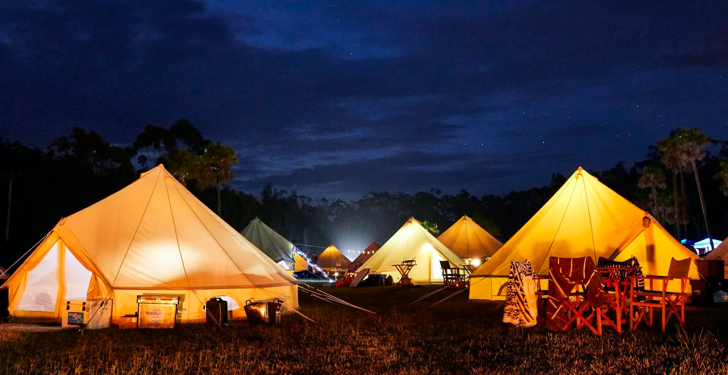 Tomorrowland Thailand Accommodation- Camping scene with illuminated tents and outdoor furniture at night.