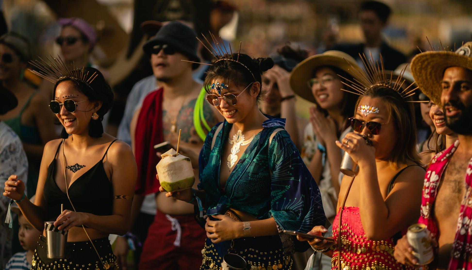 People at a festival with drinks and colorful attire at Tomorrowland Thailand Festival