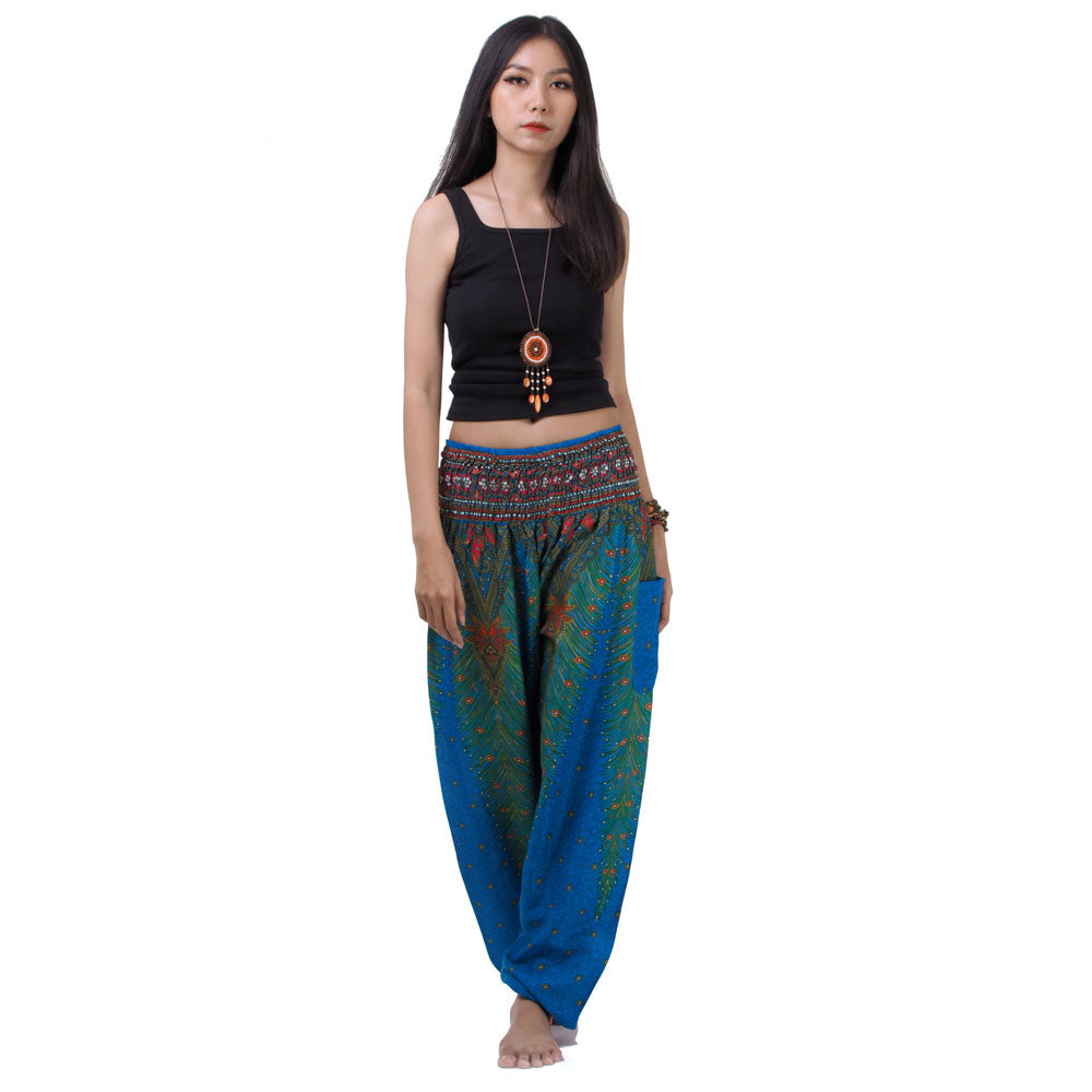 Model wearing blue Thai harem yoga pants with peacock print and black top, front view