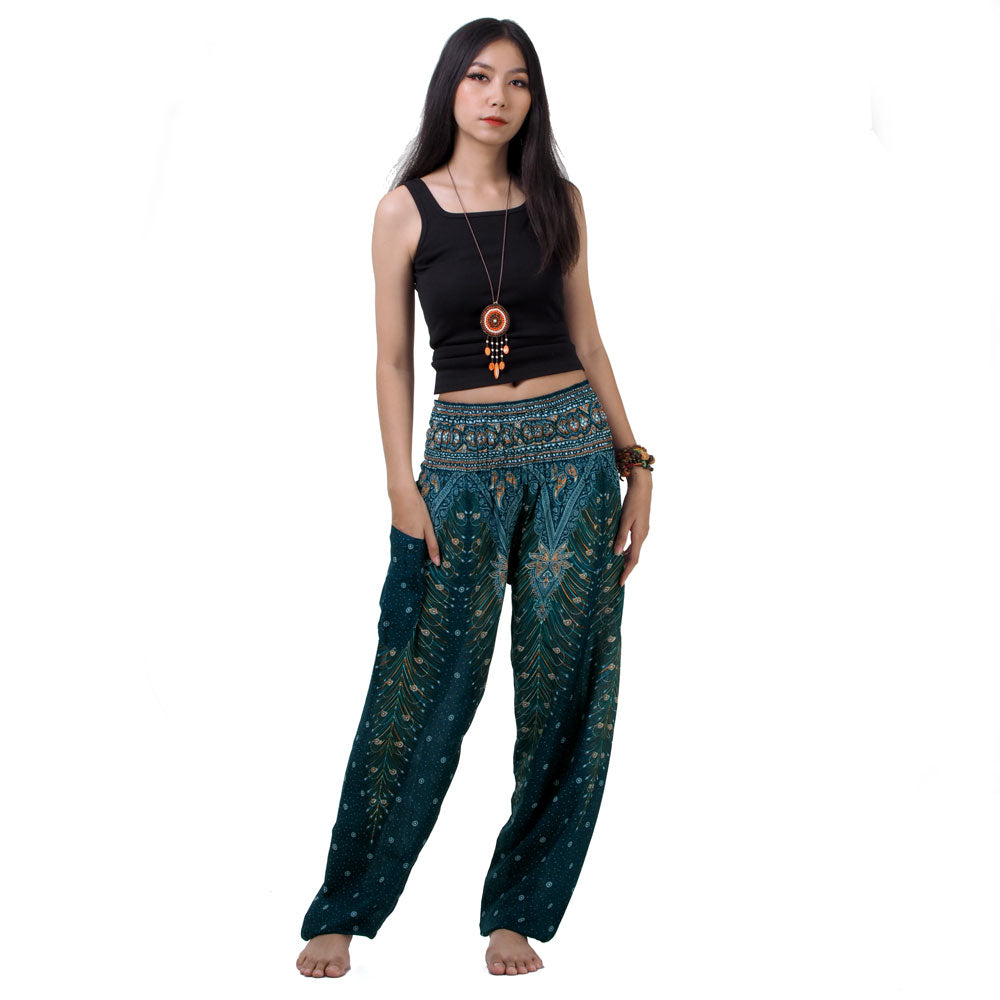 Model wearing turquoise Thai harem yoga pants with peacock print and black top, front view