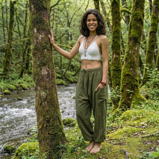 Model wearing Jungle Green pinstripe harem pants in a lush forest setting with running water.