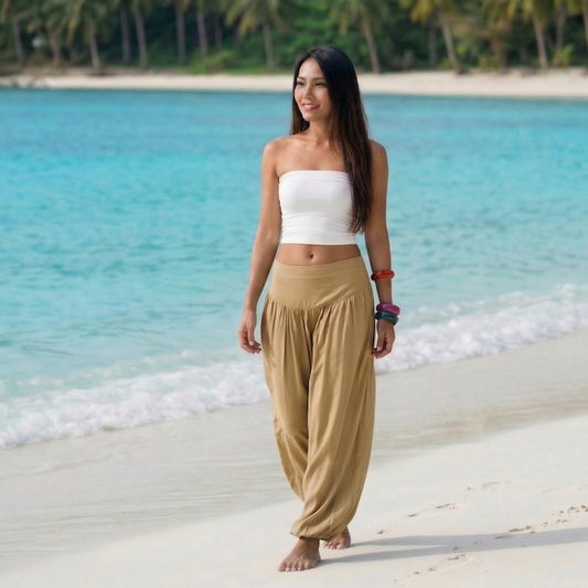 Female model in golden sands Thai harem pants walking on a Thai beach, highlighting the sophisticated boho style and dynamic textile movement.