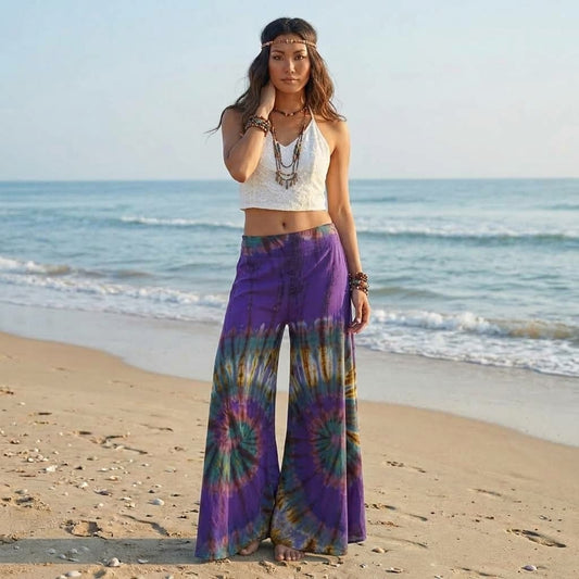 Female model posing barefoot on a sandy Thai beach wearing the vibrant Royal Purple Hippie Tie Dye Palazzo Pants.