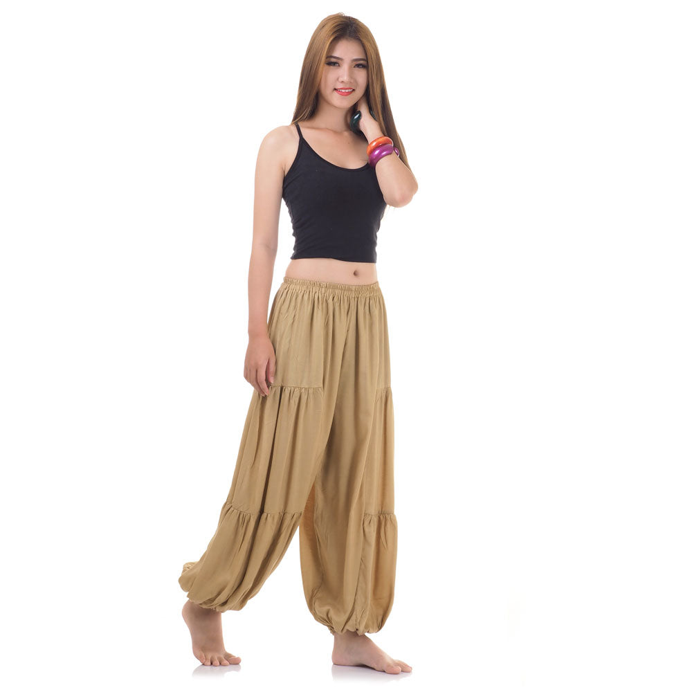 Side view of female model in beige women Thai harem yoga pants with black shirt