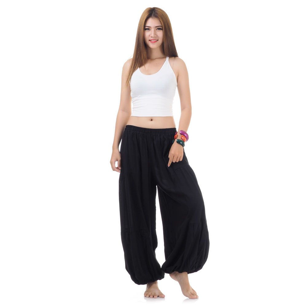 Female model wearing a black women Thai harem yoga pants with white top, front view