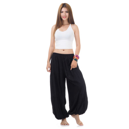 Female model wearing a black women Thai harem yoga pants with white top, front view