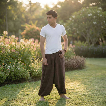 Man in a white shirt and brown Thai harem yoga pants standing in a garden