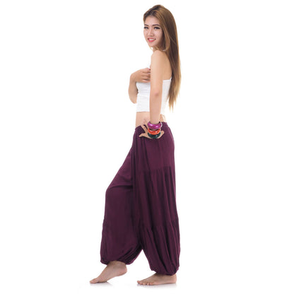 Side view of female model in  burgundy women Thai harem yoga pants with white top