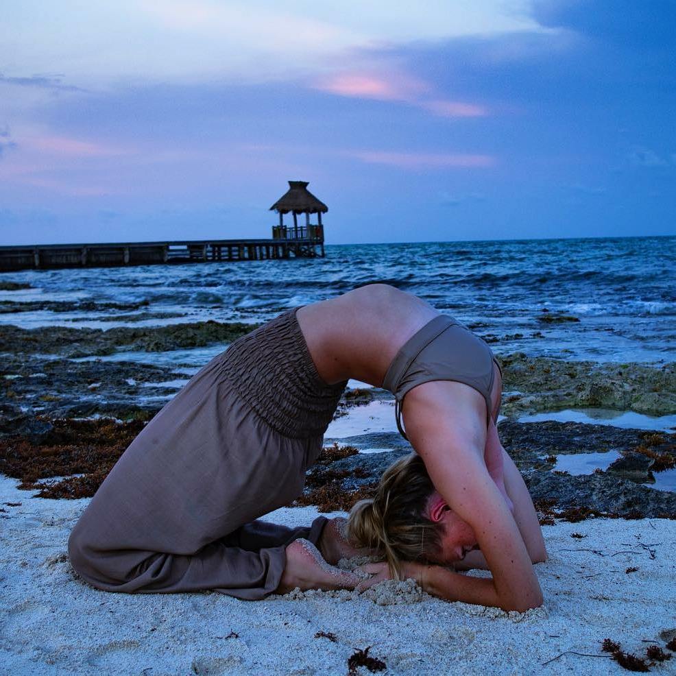 Person doing a yoga pose on a beach at dusk with wearing a my thai harem pants