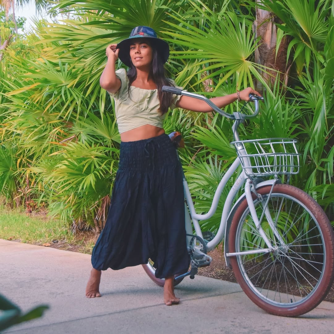 Woman with a bicycle in a tropical setting wearing black my thai harem pants