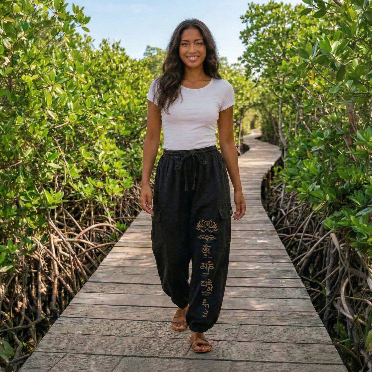 Side view of black boho lotus festival harem pants on a boardwalk highlighting the side profile and cargo pocket.