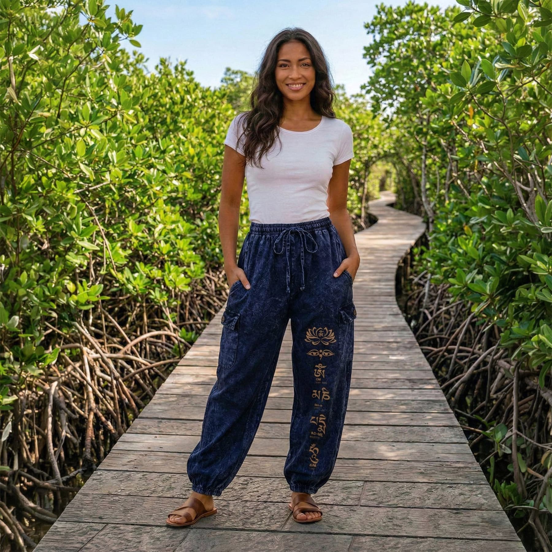 Woman posing in blue boho stonewashed lotus festival harem pants on a wooden bridge, showing the four-pocket design.