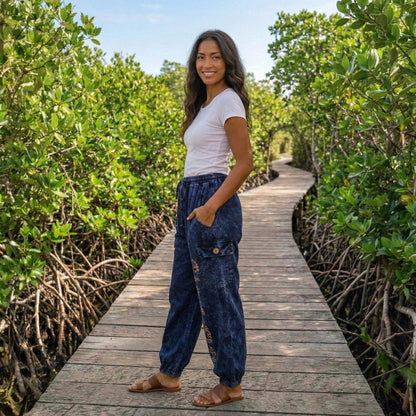 Side view of blue boho lotus festival harem pants on a boardwalk highlighting the side cargo pocket.
