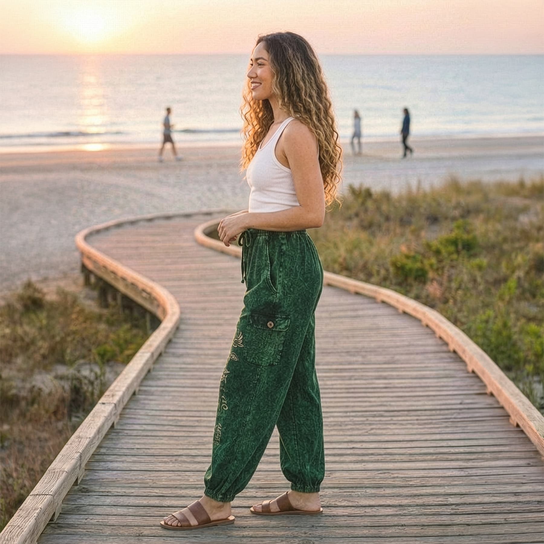 Side view of green boho lotus festival harem pants on a beach path highlighting the relaxed silhouette.
