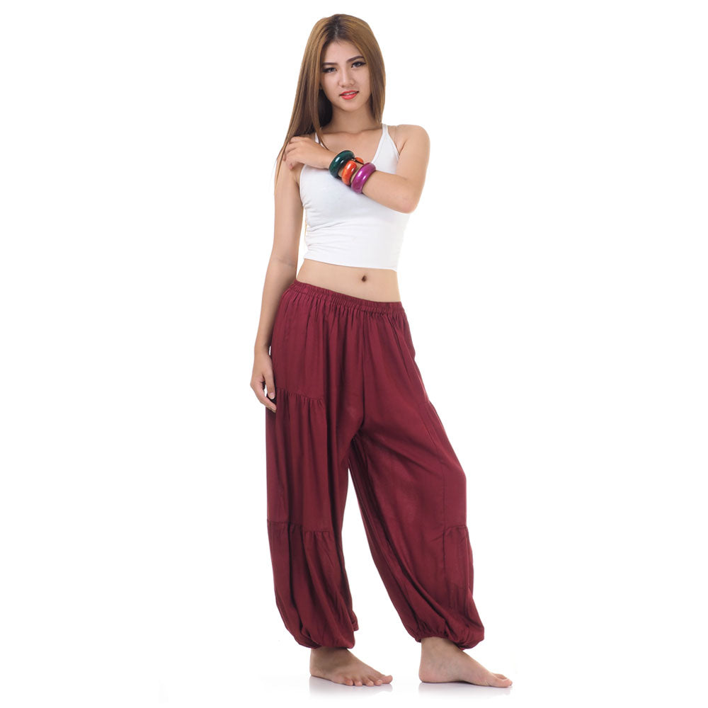 Side view of female model in maroon women Thai harem yoga pants with white top