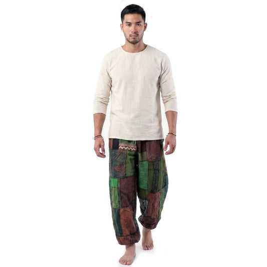 Male model wearing a green men Thai patchwork harem yoga pants with white shirt, front view