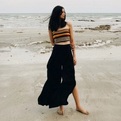 Woman in black thai wrap pants skirt and brown top standing on a thai beach