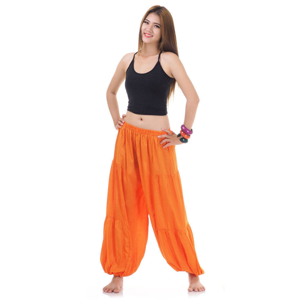 Female model wearing a orange women Thai harem yoga pants with black shirt, front view