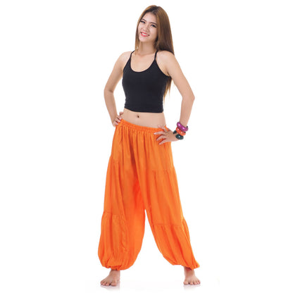 Female model wearing a orange women Thai harem yoga pants with black shirt, front view