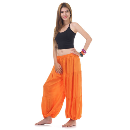 Side view of female model in orange women Thai harem yoga pants with black shirt