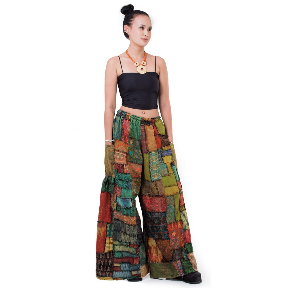 Front view of a model wearing brown patchwork wide-leg boho hippie palazzo pants on a neutral background.
