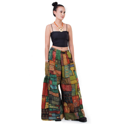 Front view of a model wearing brown patchwork wide-leg boho hippie palazzo pants on a neutral background.