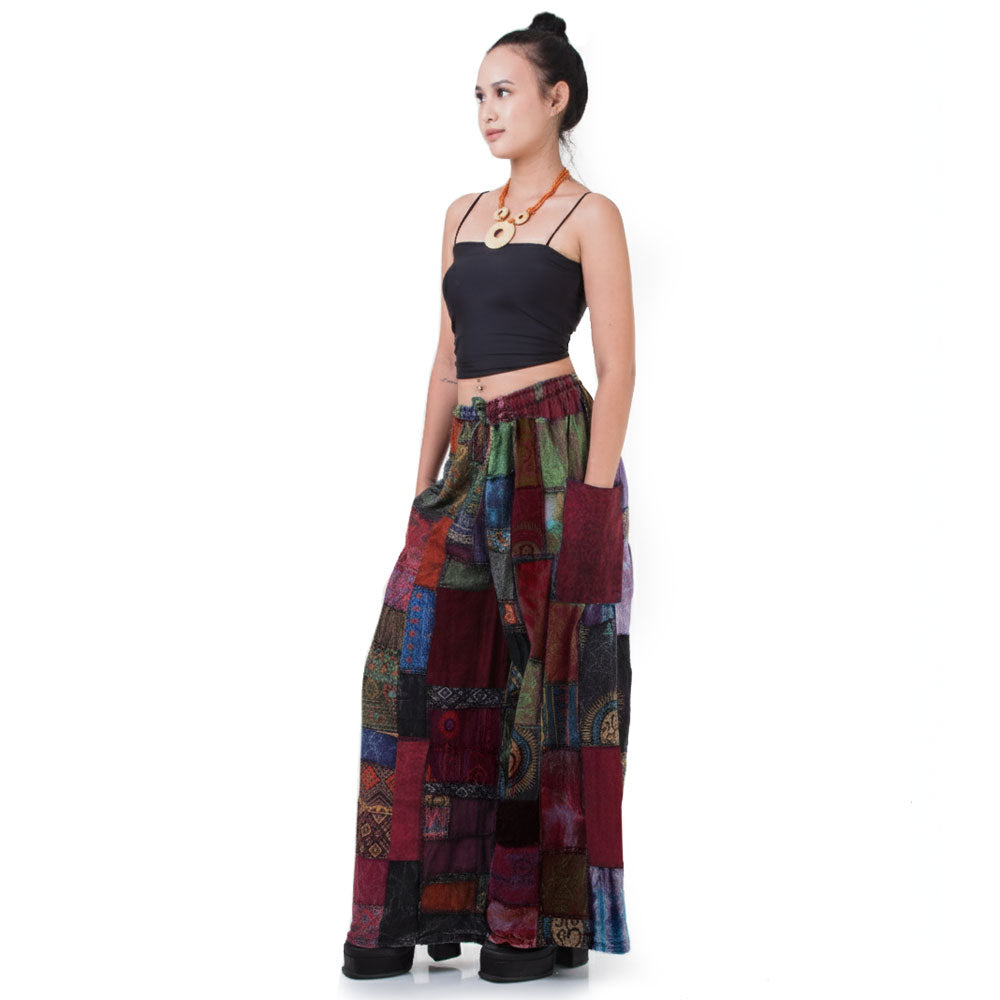 Side view: Model showcases the flowy fit of the multicolored Patchwork Hippie Palazzo Pants paired with a black shirt.