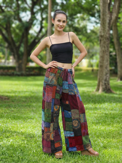 Woman wearing colorful patchwork hippie palazzo pants and a black top in a park setting