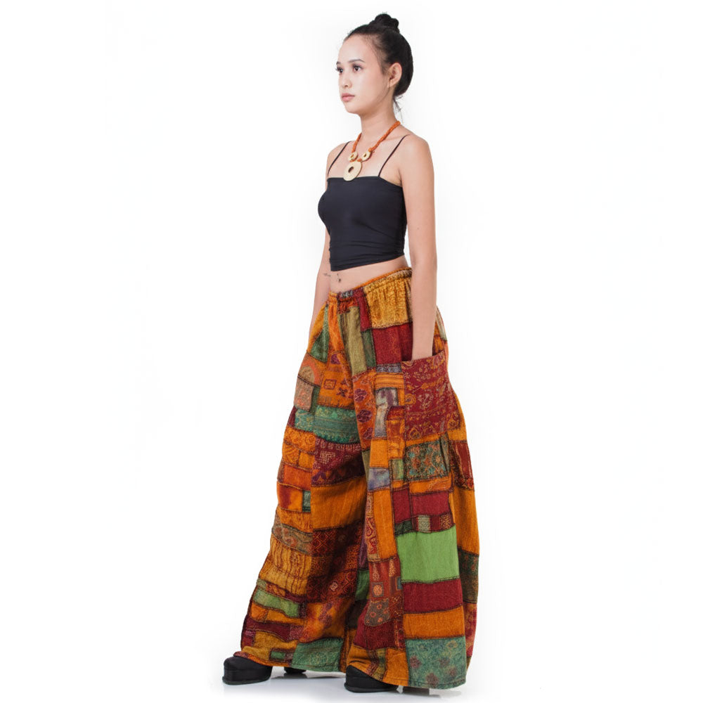 Side view: Model showcases the flowy fit of the multicolored Patchwork Hippie Palazzo Pants paired with a black shirt.
