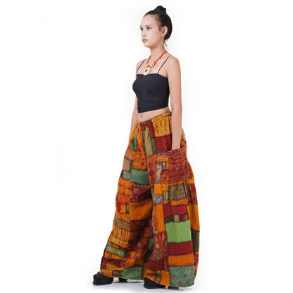 Side view: Model showcases the flowy fit of the multicolored Patchwork Hippie Palazzo Pants paired with a black shirt.