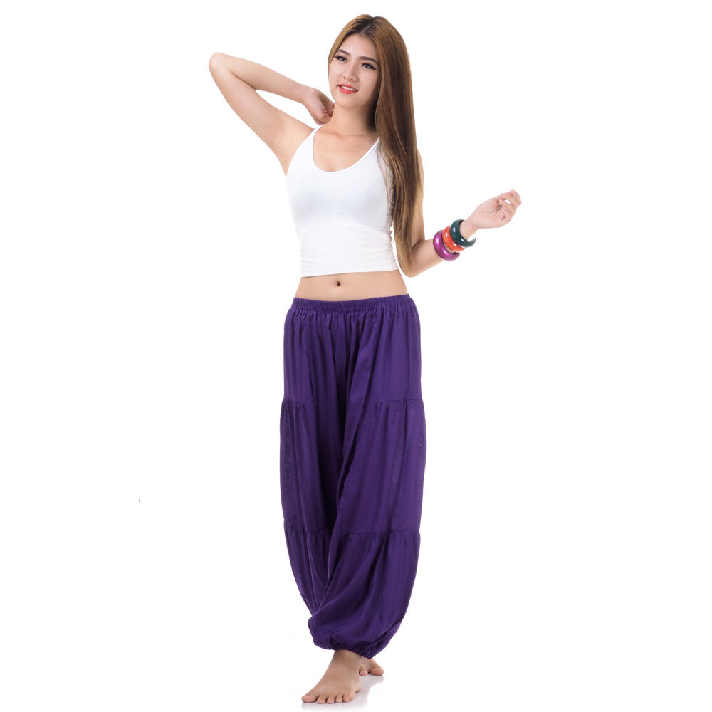 Female model wearing a purple women Thai harem yoga pants with white top, front view