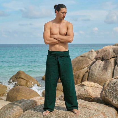 Male model posing on a beach wearing versatile Forest Green Oasis men's Thai fisherman pants in a wrap around style.