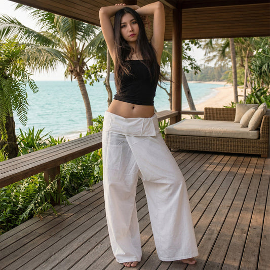 Female model standing confidently on a wooden porch by the ocean, wearing versatile Pure White Sand women's Thai fisherman pants.