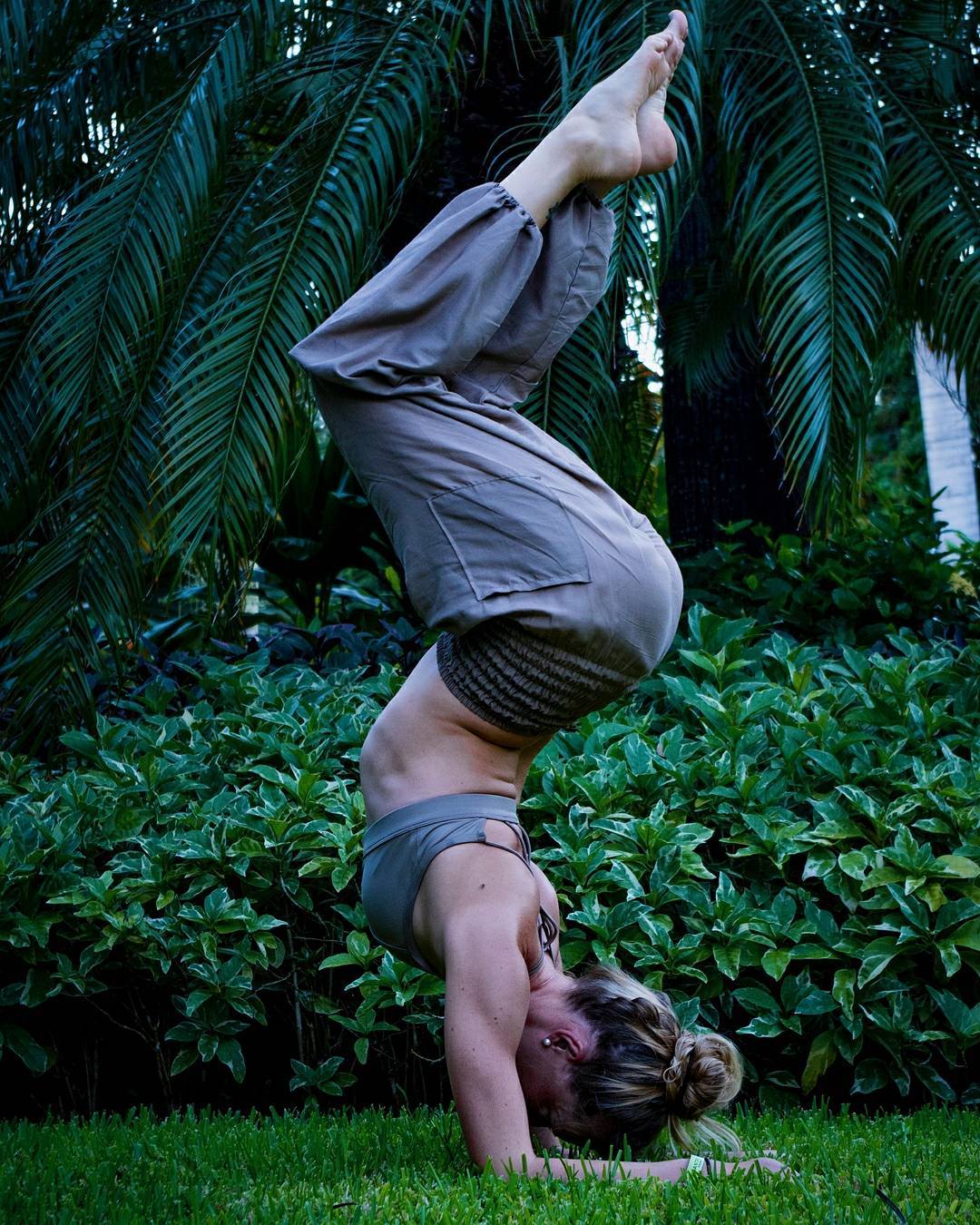 Person doing a handstand in a garden with greenery around in my thai harem pants