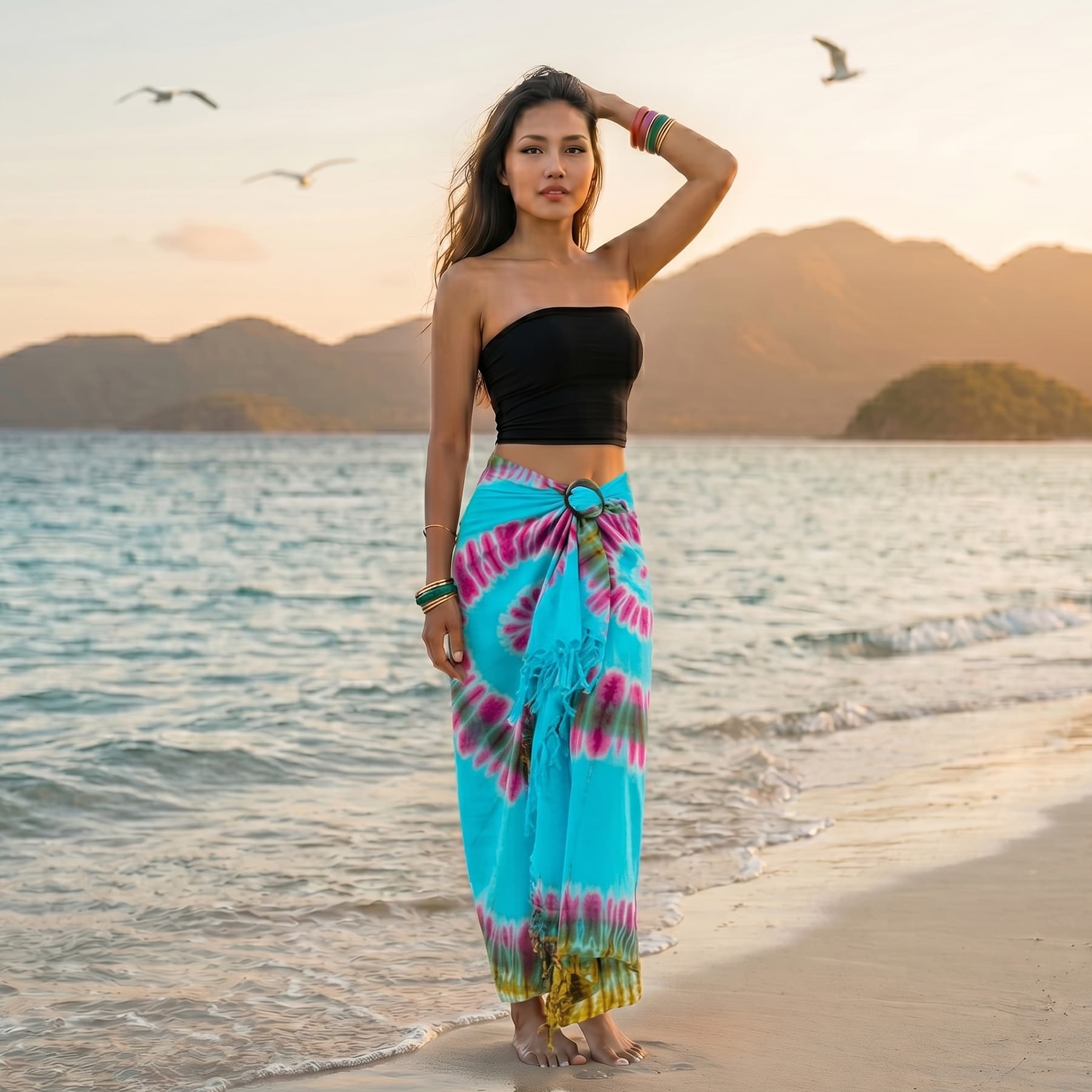 Female model walking along a tropical shoreline wearing the Blue Ocean Samui Tie Dye wrap skirt.