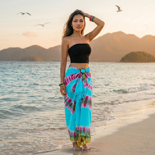 Female model walking along a tropical shoreline wearing the Blue Ocean Samui Tie Dye wrap skirt.