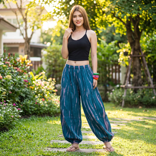 Female model standing outdoors in a green backyard garden wearing the breezy blue Women's Tie Dye Harem Pants Ocean Breeze.