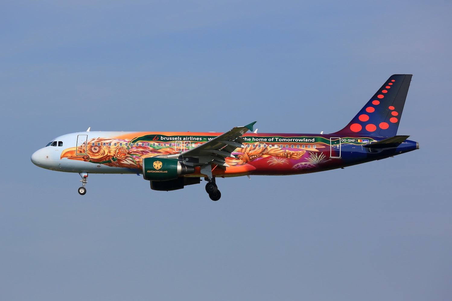 Colorful airplane with a Tomorrowland Thailand design flying against a clear blue sky