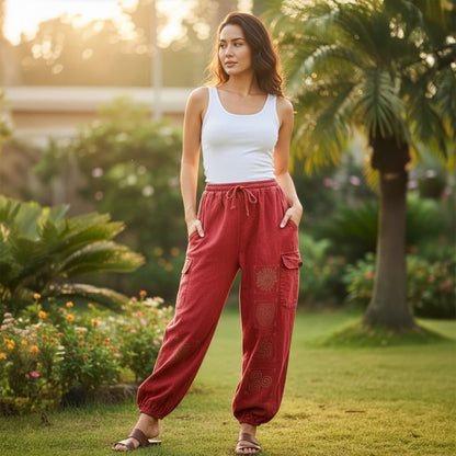 Woman posing in red boho stonewashed mandala pants in a park showing the four-pocket storage.