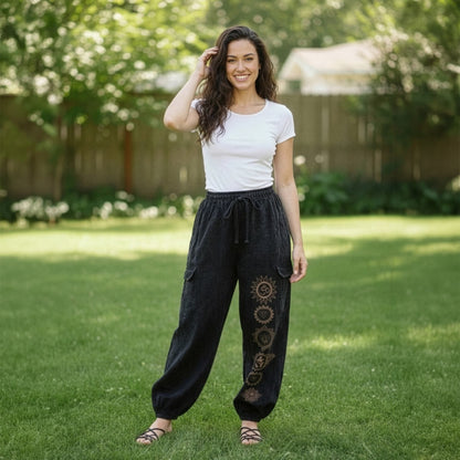 Female model wearing black boho tribal om harem pants in a park, front view.