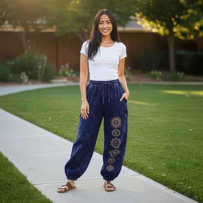 Female model wearing blue boho tribal om harem pants in a park, front view showing the cargo pockets.