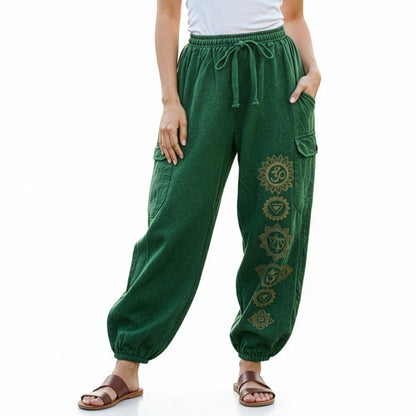 Close-up detail of green stonewashed tribal om harem pants with handcrafted symbols and cargo pockets.