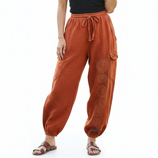Close-up of orange stonewashed tribal om harem pants focusing on the stonewashed fabric and prints.