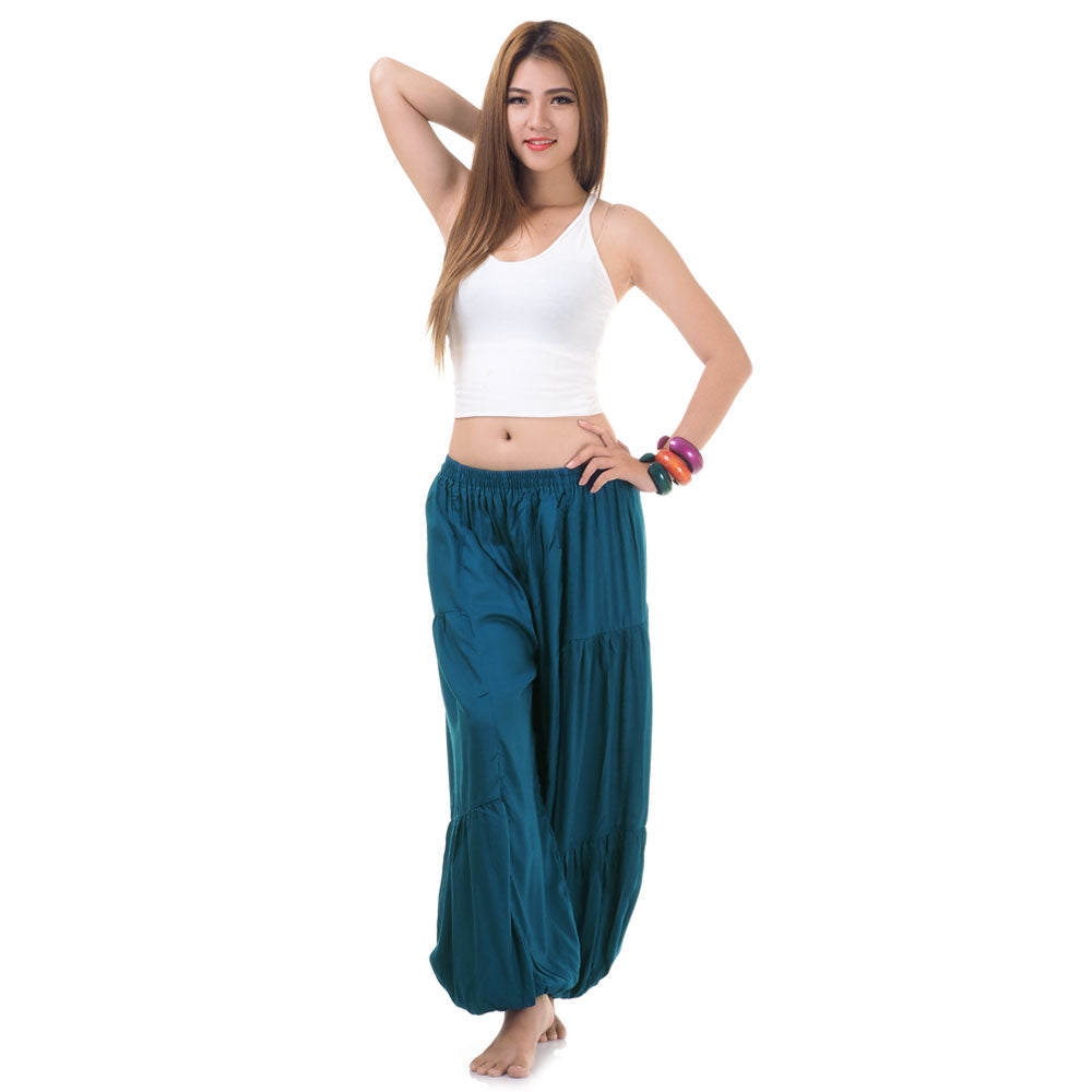 Female model wearing a turquoise women Thai harem yoga pants with white shirt, front view