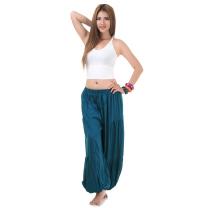 Female model wearing a turquoise women Thai harem yoga pants with white shirt, front view