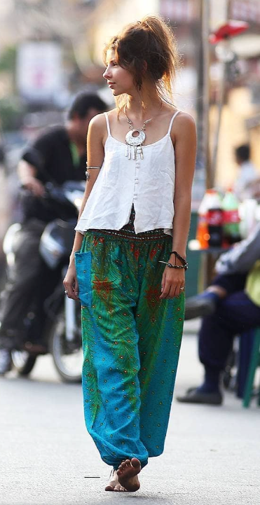 Woman in blue Thai harem yoga pants with peacock print and  white top walking on a street